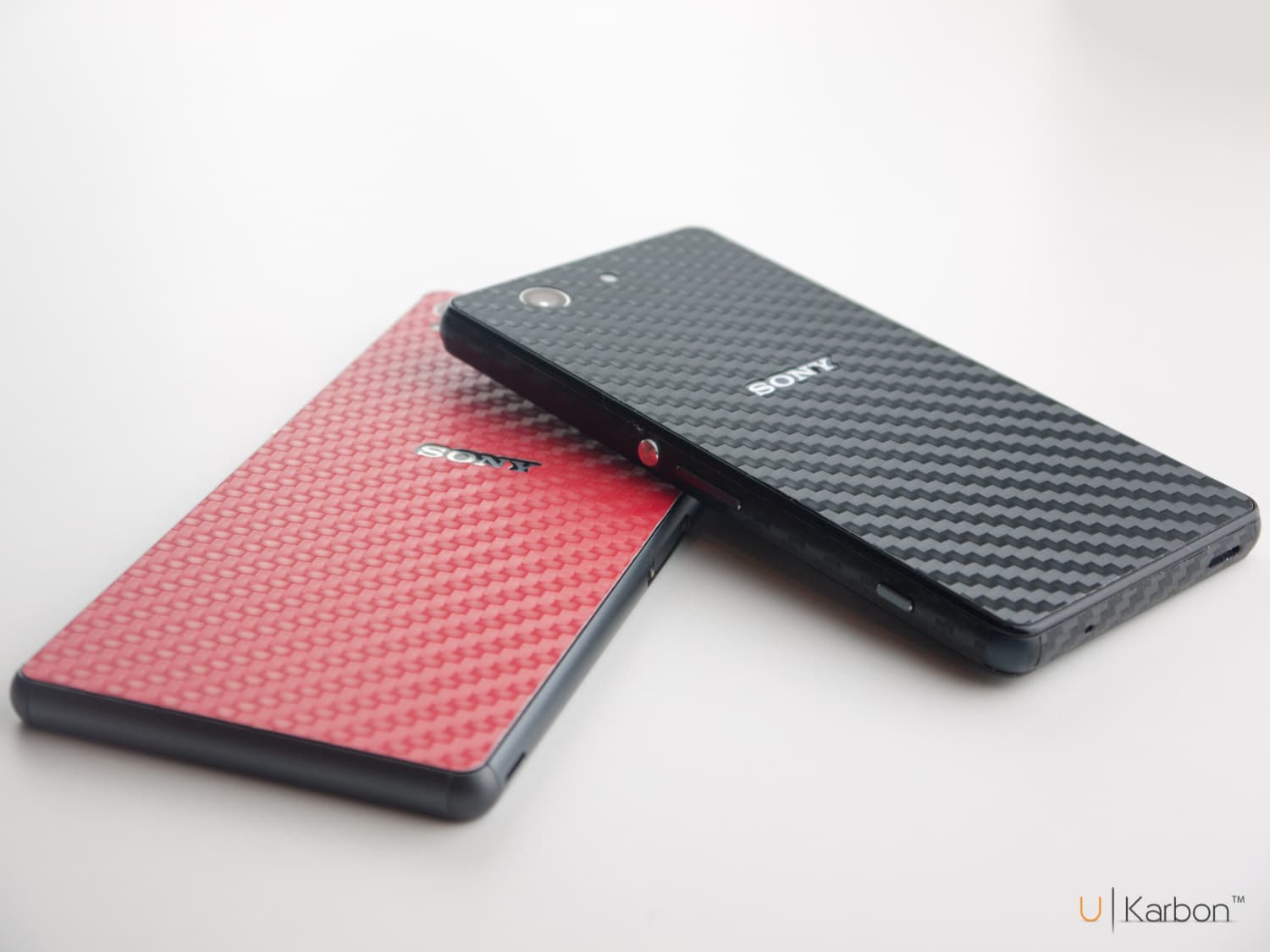 Two Sony Xperia phones in black and red carbon-fibre skins