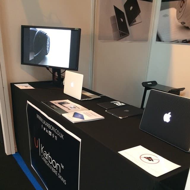 The UKarbon stand at the trade show, with a demo monitor, skinned laptops and a branded table cloth